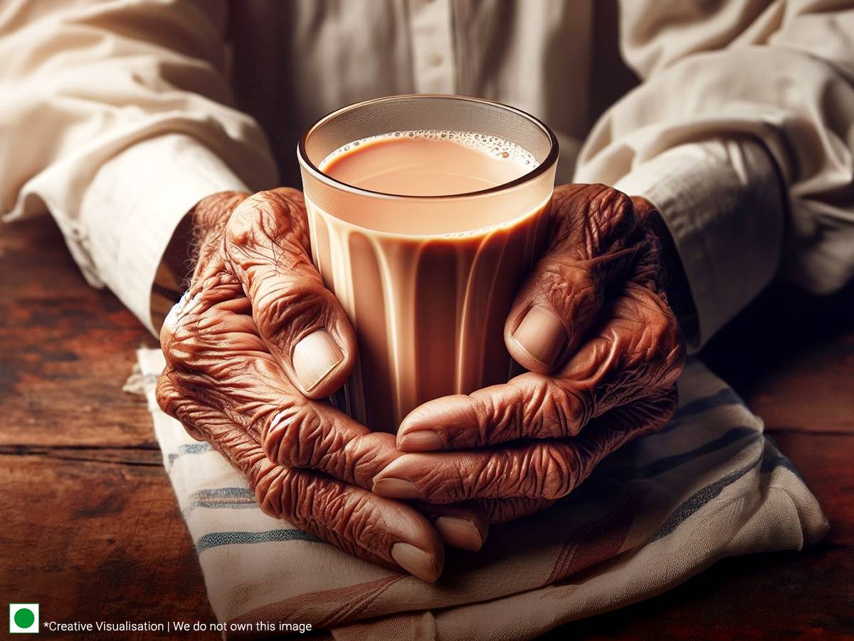 A hand holding a small cup of masala chai